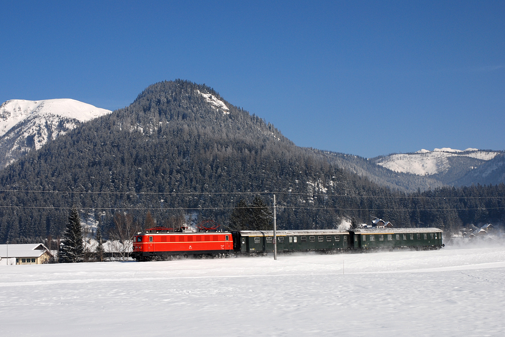 1141.21 der GEG (sterreichische Gesellschaft fr Eisenbahngeschichte) durchfhrt am 08.02.2012 mit SE 14440 von Graz nach Salzburg (Sonderzug fr eine englische Reisegruppe) das Salzkammergut und befindet sich zum Zeitpunkt der Aufnahme vor der Kulisse der Tauplitzalm im Ortsgebiet von Bad Mitterndorf.