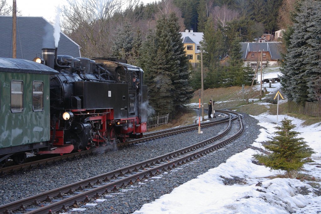 99 786 mit P1008 in Richtung Cranzahl am 30.12.2012 im Haltepunkt Neudorf. Soeben hat es ein  lokomotivisches  Pfeifkonzert gegeben! Da ich immer wieder die fragenden Blicke vieler Leute sehe, warum denn der stehende Zug solch einen  Krach  machen mu, hier eine kurze Erklrung: Das Ganze hat nichts damit zu tun, dass der Lokfhrer Langeweile hat, sondern vielmehr mit einer alten Dienstvorschrift, welche fr Zugbegegnungen in Bahnhfen ohne eigene Signalanlage eingerichtet wurde und noch aus den frhen Zeiten der Eisenbahn stammt! Die Prozedur gestaltet sich folgendermaen: Ein Zug (z.B. der talfahrende, wie hier) fhrt generell zuerst in den Bahnhof ein, whrend der bergfahrende Zug vor dem Bahnhof warten mu. Nachdem der erste Zug eingefahren ist, geht ein Mitglied vom Personal desselben zur Weiche (siehe Bild!) und stellt sie auf das freie Nebengleis. Der vor dem Bahnhof wartende Zug fragt mittlerweile mit zwei langen Pfiffen aus der Dampfpfeife nach, ob die Weiche gestellt und die Einfahrt frei ist. Ist das der Fall, antwortet die im Bahnhof wartende Lok mit der Pfifffolge  Lang-Kurz-Lang  was dem  K  im Morsealphabet entspricht und soviel wie  Kommen  heit. Nach einem kurzen Achtungspfiff setzt sich der drauen wartende Zug in Bewegung und fhrt in den Bahnhof ein. Nachdem die Weiche zurckgestellt ist, kann der im Bahnhof wartende Zug seine Fahrt fortsetzen.
Diesen Vorgang hat mir mein Grovater bereits erklrt, als ich noch ein kleines Kind war. Das in der heutigen modernen Zeit nach wie vor unverndert erleben zu knnen, verursacht bei mir immer wieder eine Gnsehaut!