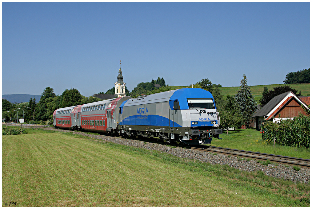 Adria Transport 2016.920 ist seit neuem im Plan B bei der GKB zu bewundern. Am Foto ist sie mit R 4366 (GKB) von Wies-Eibiswald in die Landeshauptstadt Graz unterwegs. Im Hintergrund dominiert die Kirche Eibiswald. 09.07.2011