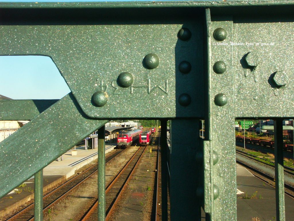 Gerader geht es nicht, der Blitz kam NICHT zum Einsatz:

Blick durch die  Luftbrücke  zu Hof, den langen Fußgängersteg über den ganzen Bahnhof, der ja bald ersetzt werden soll. Hinten stehen 612 und 218 (an diesem 6.09.2010 waren sogar 2x218 dran) und oben auf dem Knotenblech der Brücke kann man in der Abendsonne gut MH 34 lesen, da weiss man gleich wer wann diese Stahlbrücke hergestellt hat...

Aber sicher sind die Züge jetzt einfach viel zu klein oder es ist immer noch schief, auch wenn ich es nicht gerade hinbekomme da ich nur gradweise richten kann. Ich konnte auch nicht weiter zurück gehen, denn der Steg ist nur 1,40 Meter breit oder so..... Dies nur um allen mir denkbaren negativen Aspekten dieser Aufnahme vorzubeugen. Aber Euch fällt sicher noch mehr ein!