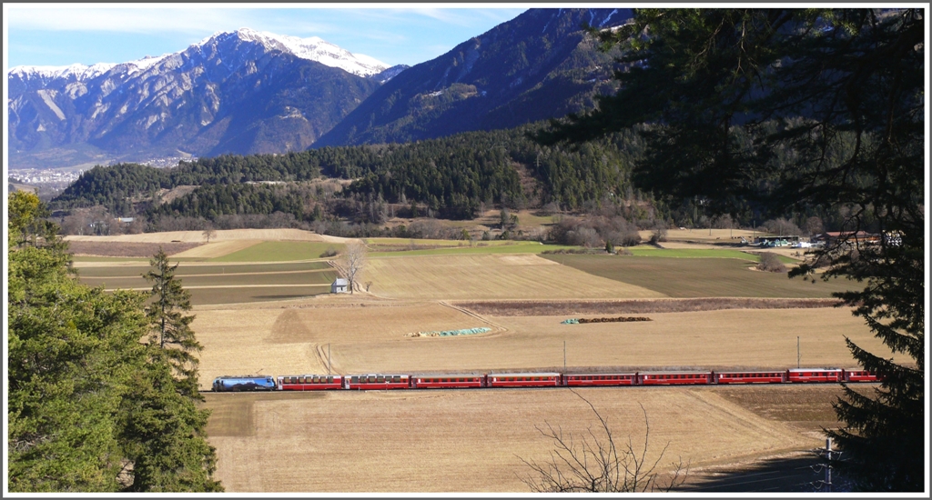 RE1136 aus St.Moritz mit Ge 4/4 III 647 *Grsch  fhrt an der Kapelle Sogn Mang bei Bonaduz vorbei. Im Hintergrund ist die Stadt Chur sichtbar und darber der Montalin. Die Aufnahme entstand vom Gletscherhgel Bot Danisch. (09.02.2011)