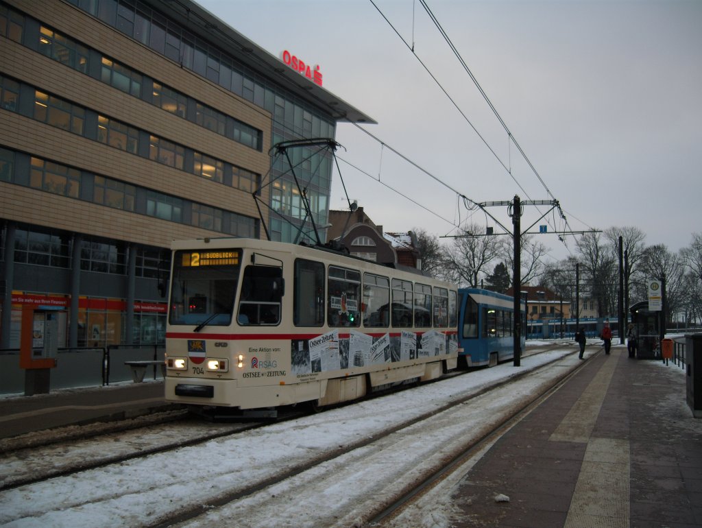 T6A2 704 Hst Schrderplatz
Die Bahn ist mit einer besonderen  Mauerfall -Gedenkfolie beklebt: Zeitungsausschnitte um den Herbst 1989, die an den Mauerfall erinnern sollen. Innen sind 4 der gepolsterten durch originale Plastesitze (rot) ersetzt worden. Fr den verwhnten A** h.. Fahrgast im harten Winter eher unangenehm, ist es fr die Straenbahnliebhaber schon etwas Besonderes :)=
13.Januar 2010