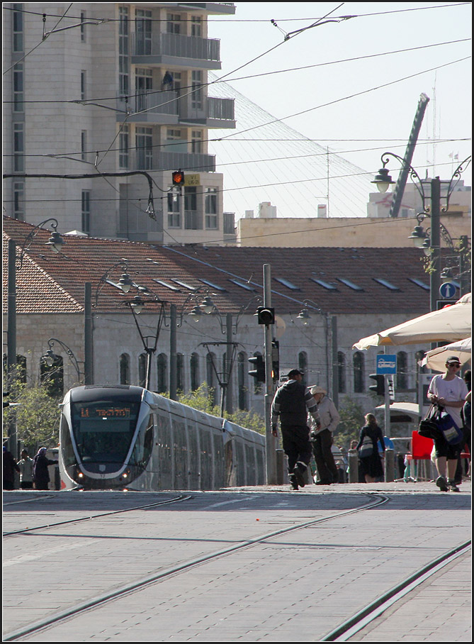 . Nur scheinbar vieräugig -

Ein Straßenbahnzug an der Station 'Mahane Yehuda'. Oben in Bildmitte ein kleiner Vorgeschmack auf das kunstbaumäßige Highlight der Jerusalemer Straßenbahn.

26.03.2014 (M)