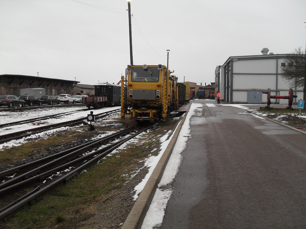 07.12.2013. Neben der Zufahrtstraße zu den Parkplätzen (Siehe Schild rechts) stand zum Nikolausfahrten die Gleisstopfmaschine in Benndorf abgestellt. Vor, sowie auch nach den Nikolausfahrten gab es noch einiges zu erneuern und zu stopfen. Hierzu gehört die Gleisverbindung Bocksthal-Zirkelschacht, der Bahnhof Zirkelschacht und die Gleise zwischen Thondorf und Siersleben.