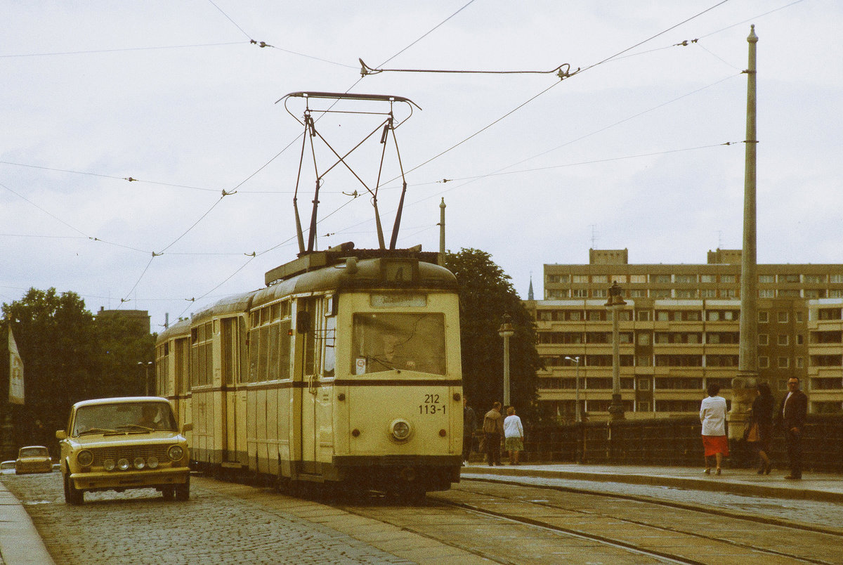 12.06.1985 Straßenbahn Dresden: ein Dreierzug der Linie 4 mit Tw 212 113 fährt nach Johannstadt über die Georgi-Dimitroff(Augustus)-Brücke. Da war die Fahrt nach Pillnitz mit der Überquerung des  Blauen Wunders  schon Geschichte. Und  Ja , der Lada fährt wirklich ohne vorderes Kennzeichen nebenher. 