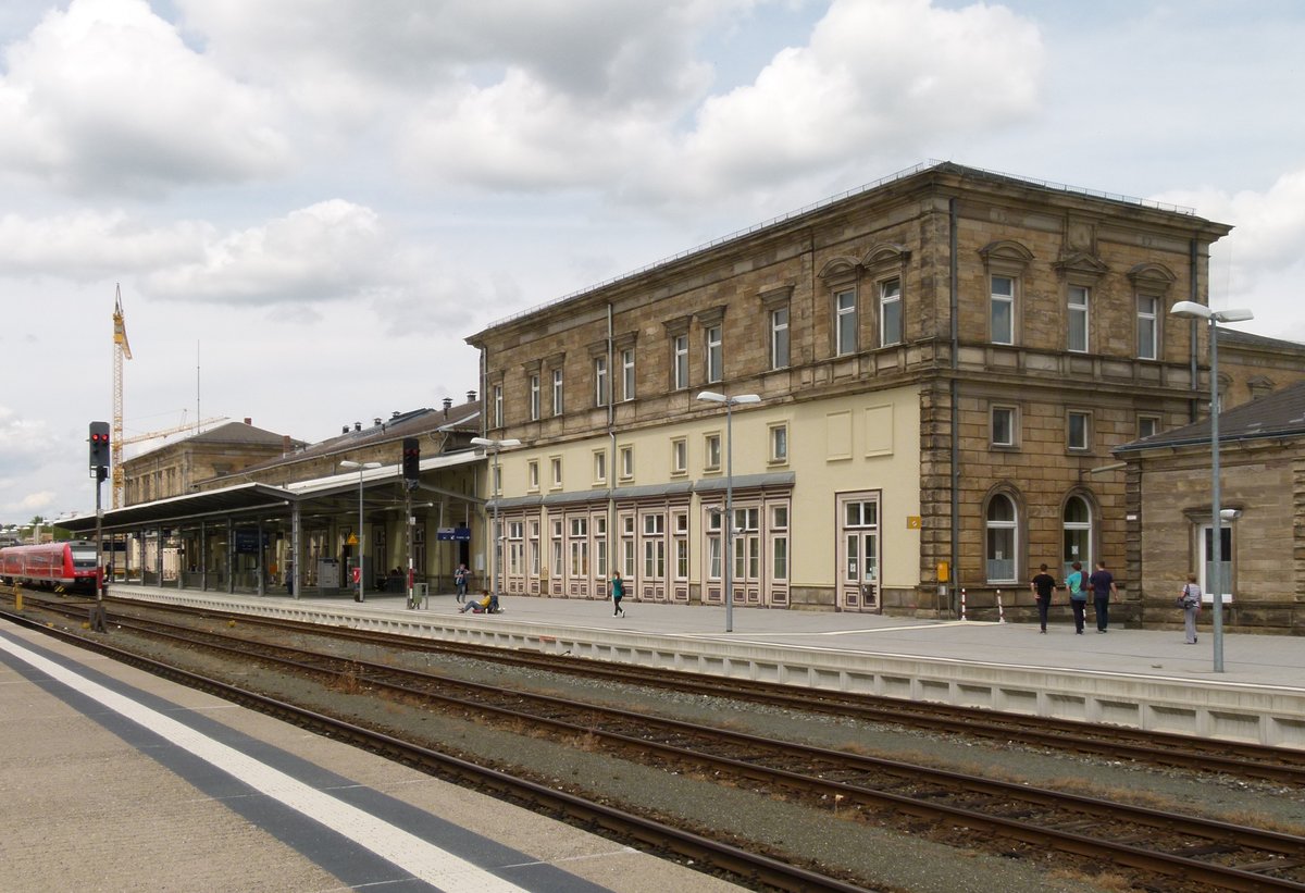 19.07.2011, Hof, Hauptbahnhof. Vor dem hell gestrichenen Gebäudeteil befand sich ehemals ein denkmalgeschütztes Dach. Ganz links zeigt sich der der Franken-Sachsen-Express RE 3791 nach Dresden. 