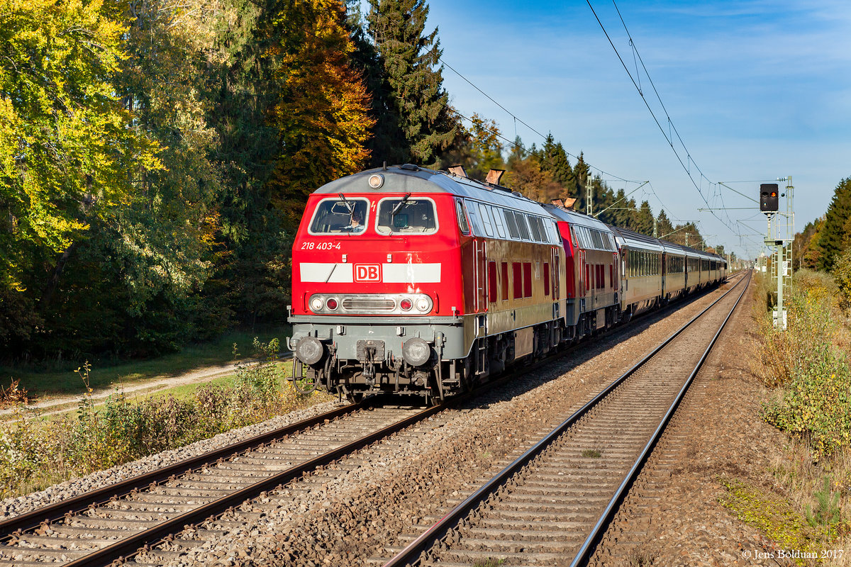 218 403 glänzt in der Herbstsonne, als sie am 13.10.2017 mit einer Schwesterlok den EC 192 von München nach Lindau durch den Schöngeisinger Forst westlich von Fürstenfeldbruck zieht. Aufgenommen am S-Bahn-Haltepunkt Schöngeising