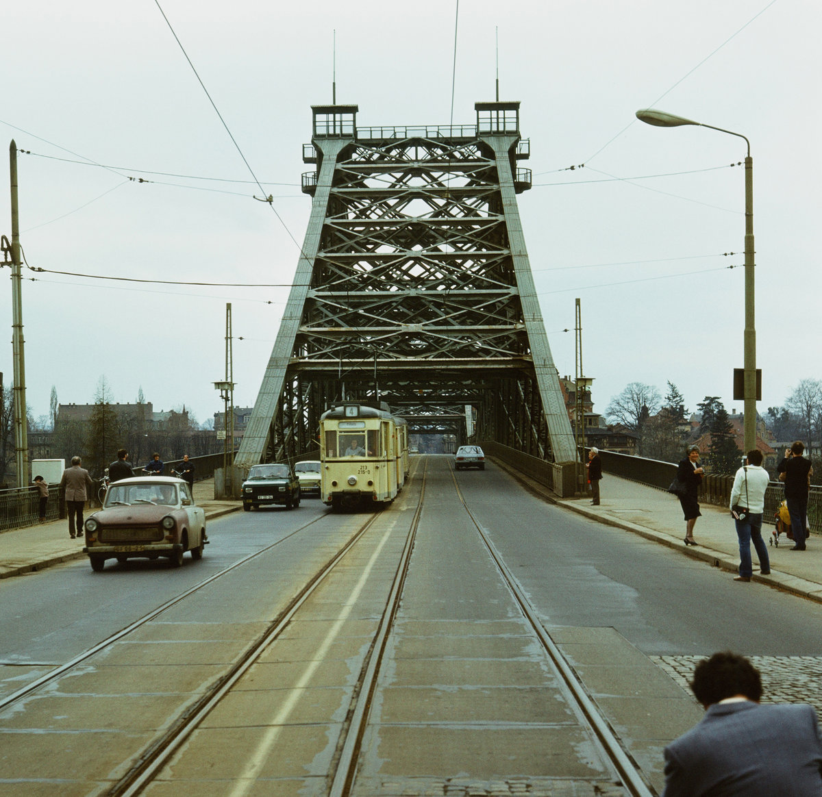 8. April 1985, Dresden: Die  Sächsische Zeitung  vom 23./24. März 1985 veröffentlichte offiziell die vom  Buschfunk  schon lange verkündete endgültige Stilllegung des Straßenbahnverkehrs über das Blaue Wunder, die Blasewitz-Loschwitzer Elbbrücke, ab 9.April 1985. Einige Fotografen halten an diesem trüben Ostermontag die letzten Betriebsstunden noch im Bilde fest. Der ruhige Straßenverkehr stört sie dabei kaum. Tw57 213 215 bringt seinen Dreierzug sicher ans linke Elbufer.  