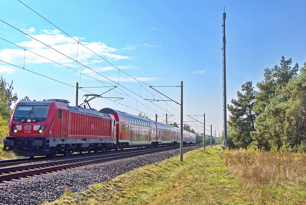 An der Siedlung Hubertusnahe der  Gemeinde Schönefeld bei Berlin, fährt am 19. September 2024 auf der Strecke von BER - Berlin Brandenburg Airport nach Berlin Gesundbrunnen ein Regionalzug als FEX (Flughafen-Express Berlin) mit der Lok 147 006.
</p>Ein Gruß geht zurück an den freundlichen Triebfahrzeugführer! 