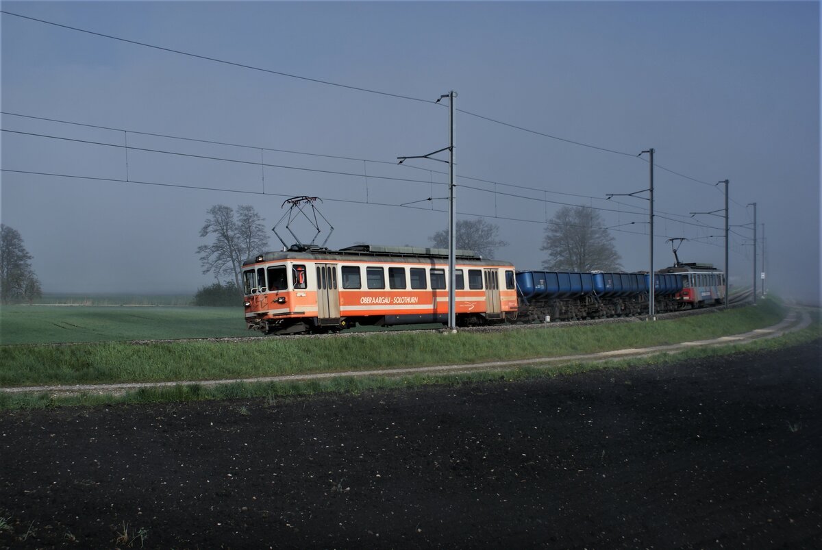 ASM BTI Aare Seeland mobil AG Biel-Täuffelen-Ins-Bahn: Be 4/4 302 + Fa 572 + Fa 571 + Fa 576 + Be 4/4 304, Zug 8238 Sutz-Finsterhennen, Lüscherzmoos (km 12,4), 3. Mai 2021. An diesem Morgen lag noch Nebel, der erst begann sich aufzulösen. Hinter den Bäumen am Mooskanal verschwanden die Felder im Nebel. 