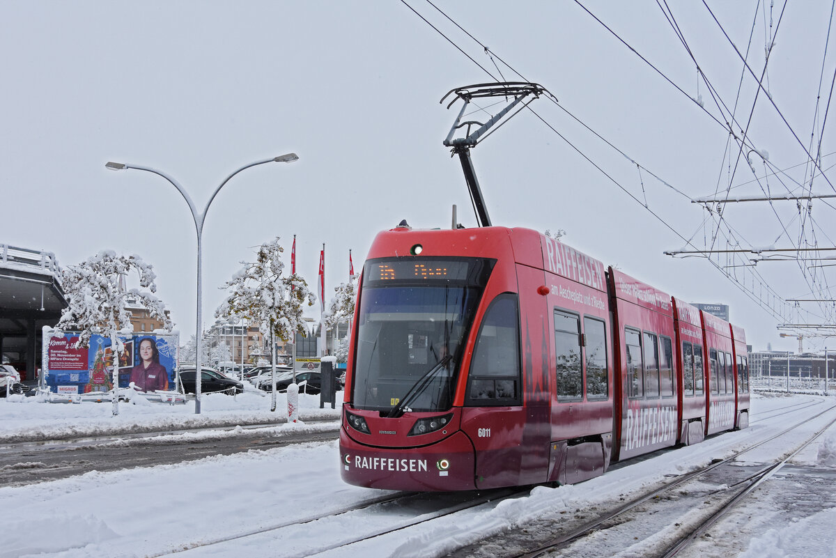 Be 4/6 Flexity 6011 mit der Werbung für die Raiffeisenbank, auf der wegen dem starken Schneefall und vielen gesperrten Strecken umgeleiteten Linie 16, fährt am 22.11.2024 zur Endstation M-Parc, beim Depot Dreispitz. Aufnahme Basel.