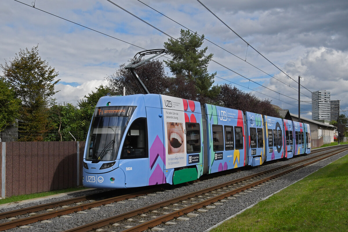 Be 6/8 Flexity 5034 mit der Werbung für Universitäres Zentrum Basel für Zahnmedizin (UZB), auf der Linie 14, fährt am 30.09.2024 zur Haltestelle Kästeli. Aufnahme Pratteln.