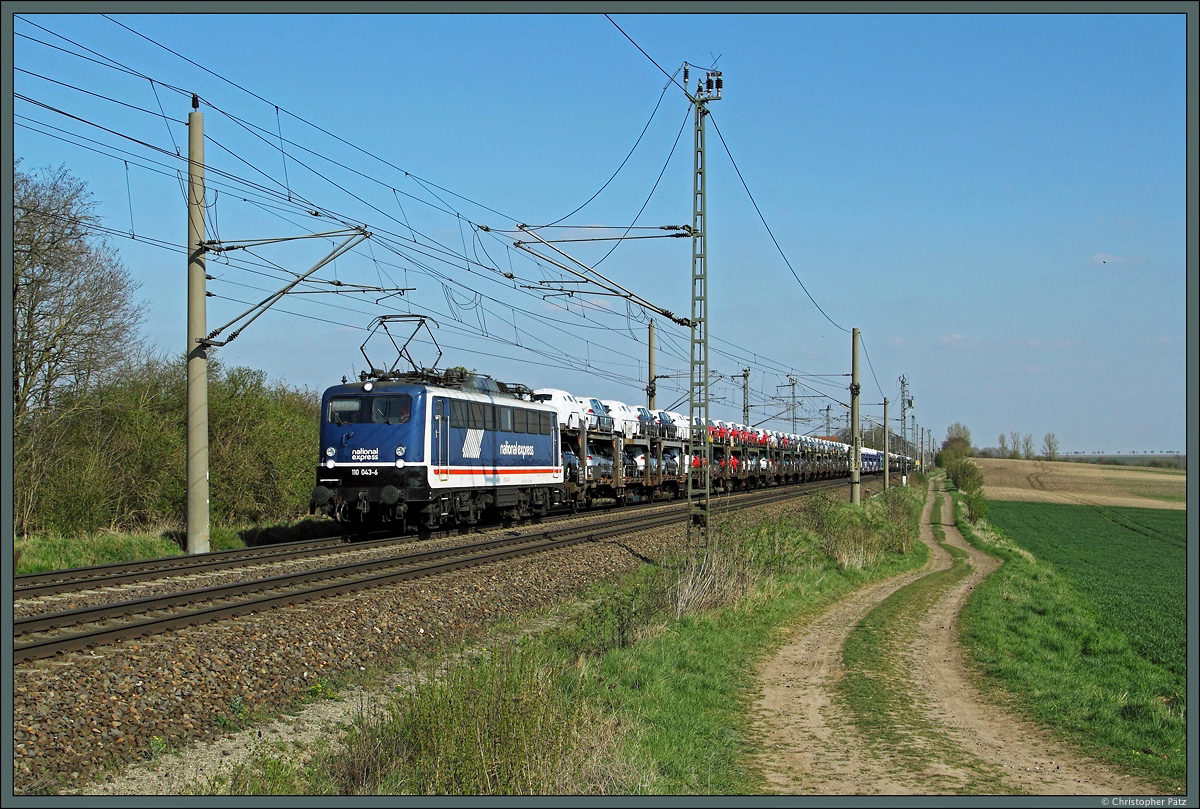 Bei Wellen zieht 110 043-6 der PRESS (in National Express-Lackierung) einen Autozug Richtung Niedersachsen. (19.04.2015)