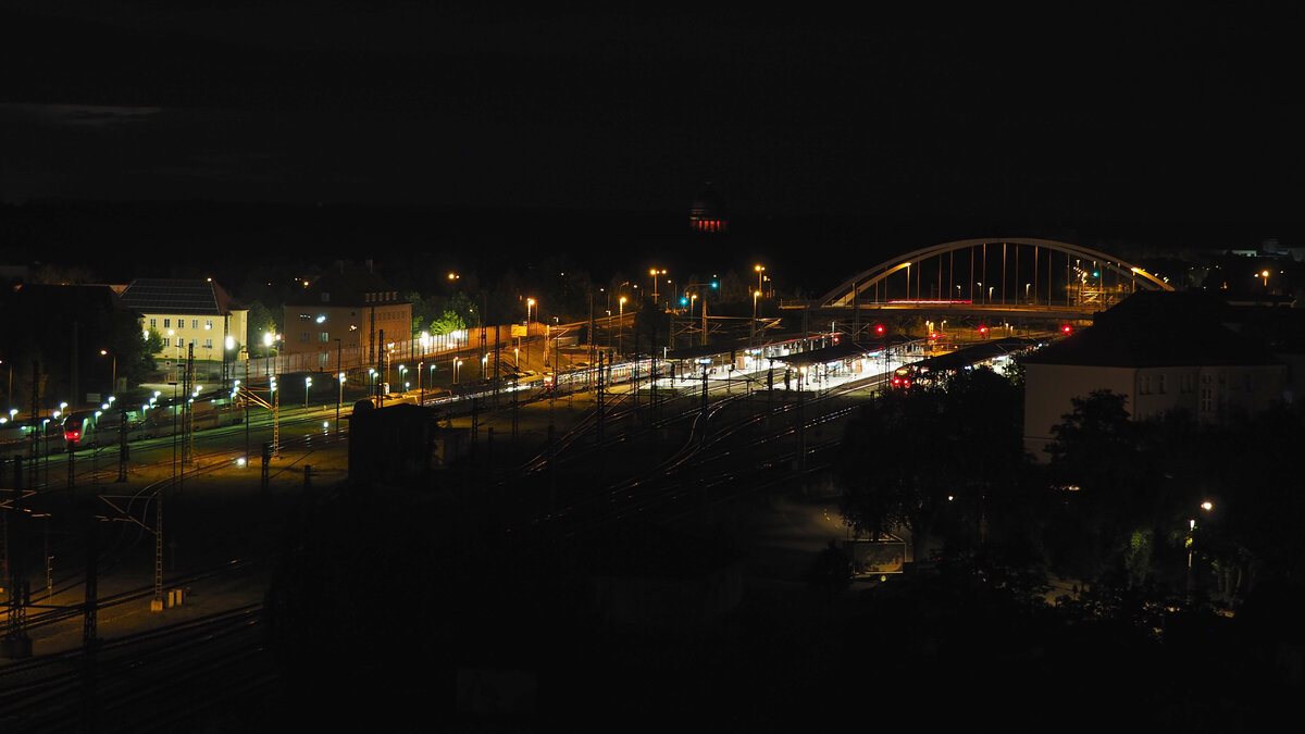 Blick auf den Dessau Hbf und sein südliches Gleisvorfeld bei Nacht.
Blickrichtung Nord.
Im Hintergrund ist rot das Mausoleum des Tierparks zu sehen, die Abstellgruppe und die Umgehungsstraße.
Aufgenommen vom Räucherturm gegen 23 Uhr.

Im Vergleich zu 2009 hat sich eigentlich nur die Belichtung div. Gebäude verändert: https://www.bahnbilder.de/bild/deutschland~bahnhoefe-a---e~dessau/281572/blick-auf-den-dessau-hbf-und.html

Dessau, der 06.07.2024