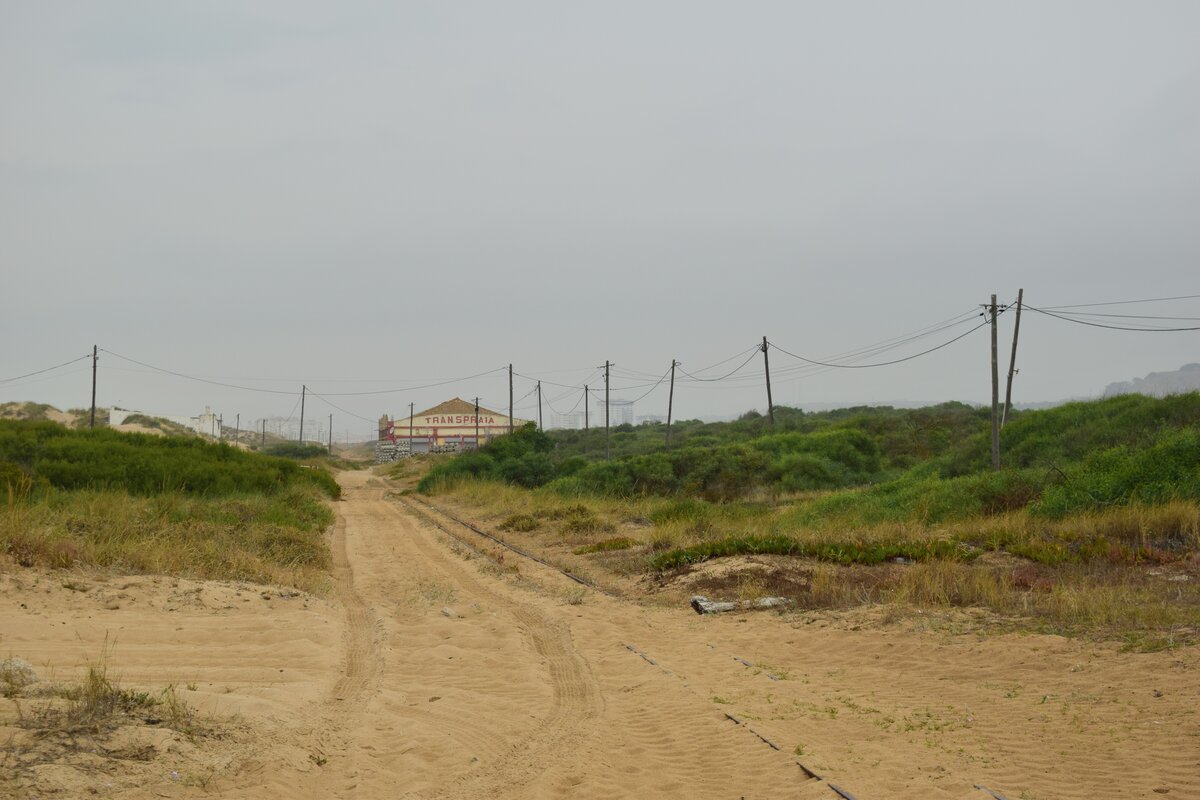 Blick auf die Strecke des Minicomboio da Caparica zwischen den Haltestellen Rainha und Praia da Rivieria. Die Bahnstrecke wurde zwischen 1960 und 1962 als touristische Attraktion erbaut. 2008 wurde das erste mal über eine Stilllegung diskutiert die jedoch abgewendet werden konnte. Zu Beginn von Corona wurde der Betrieb eingestellt und bis heute nicht wieder aufgenommen. Es gibt jedoch gute Hoffnung das bald wieder Bahnen am Strand entlang fahren, denn die Strecke samt Fuhrpark wurde an jemanden verkauft der den Betrieb wieder herstellen möchte. 

Costa da Caparica 28.06.2024