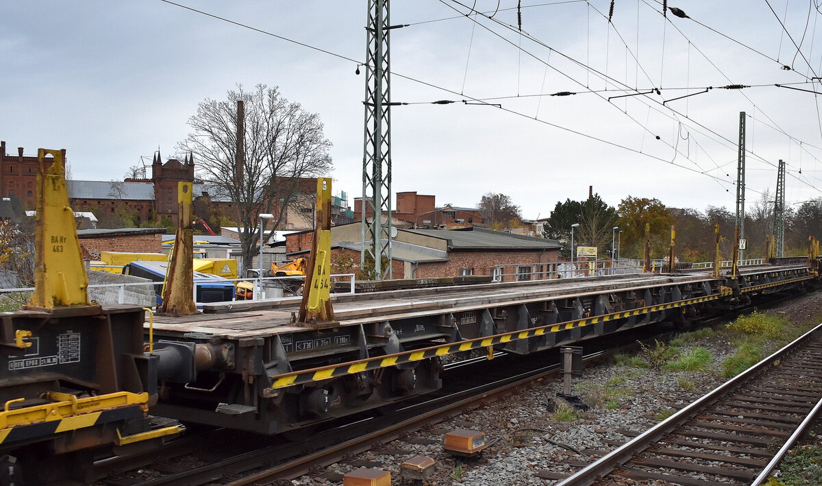 DB Cargo mit einem ihrer Drehgestell-Flachwagen (Oberbaustoffwagen) mit vier Radsätzen und Niederbindeeinrichtungen. Der Schwellentransportwagen dient beim Gleisneubau oder bei der Gleisinstandsetzung dem Transport von Schwellen für Schienenumbauzüge nach den Umbauverfahren UM und UH. Seitlich angebrachte Portalkranschienen und Überfahrschienen zwischen benachbarten Schwellentransportwagen ermöglichen die Befahrbarkeit mit Portalkränen. Im Bild der Wagen mit der Nr. 82 80 D-DB 4727 524-7 Slps 464 in einem Ganzzug am 25.11.24 Höhe Bahnhof Magdeburg-Neustadt.