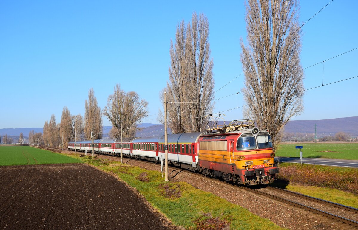 Die 240 120-er Laminátka ist auf dem Weg von Kozározve nach Bratislava hl. Stanica mit dem Eilzug R836  Urpín  kurz vor Hronské Kľačany. Heute ist es in der Slowakei selten, eine solche Lokomotive an der Spitze eines Personenzuges zu sehen.
Hronské Kľačany, 30.11.2024.