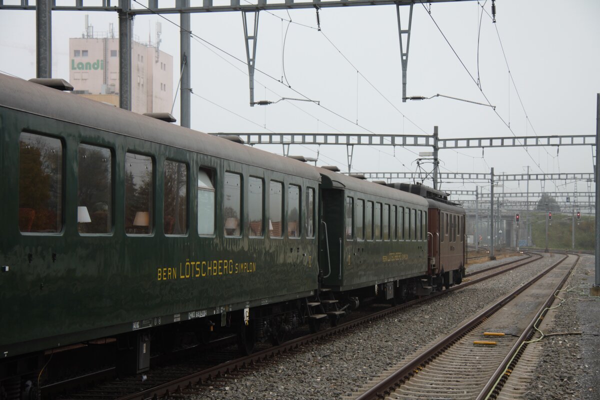 Die Ae 4/4 der BLS steht am Zugschluss. Ich konnte die Szene am 26.10.2024 im Bahnhof von Romont vom Peron aus fotografieren. Auch wenn der Elektrooltimer als Angstlok mitgeführt wurde, entsteht der Eindruck, als würde der Zug auf die Abfahrt in diese Richtung warten.