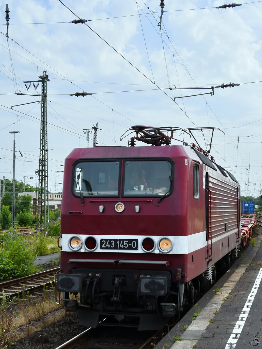 Die Elektrolokomotive 243 145-0 ist hier Ende Juni 2024 mit einem fast leeren Container in Wanne-Eickel zu sehen.