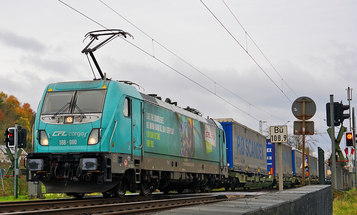 Die  Hummel  188-060 von CFL Cargo Deutschland überquert am 23.11.2024 einen Bahnübergang auf der rechten Rheinstrecke südlich von Unkel. Die Seitenaufschrift inkl. einer Hummel soll symbolisieren, wie hart CFL Cargo rund um die Uhr für unsere Zukunft unterwegs ist.