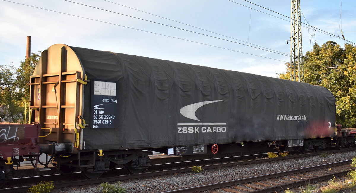 Drehgestellflachwagen mit vier Radsätzen, verschiebbarem Planenverdeck, jedoch ohne Rungen für den Transport nässeempfindlicher Güter der slowakischen ZSSK Cargo mit der Nr. 31 RIV 56 SK-ZSSKC 3540 039-5 Rils in einem gemischten Güterzug am 17.10.24 Höhe Bahnhof Magdeburg Neustadt.