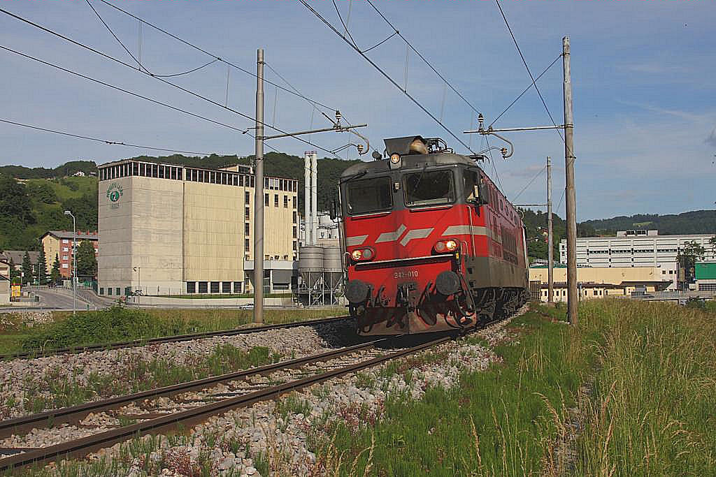 Einfahrt in den Bahnhof Lasko. Im Hintergrund sind die Gebäude der gleichnamigen Brauerei zu sehen. Altbau Elektrolok der SZ 342010 ist mit einem Schnellzug am 29.5.2011 in Richtung Maribor unterwegs.