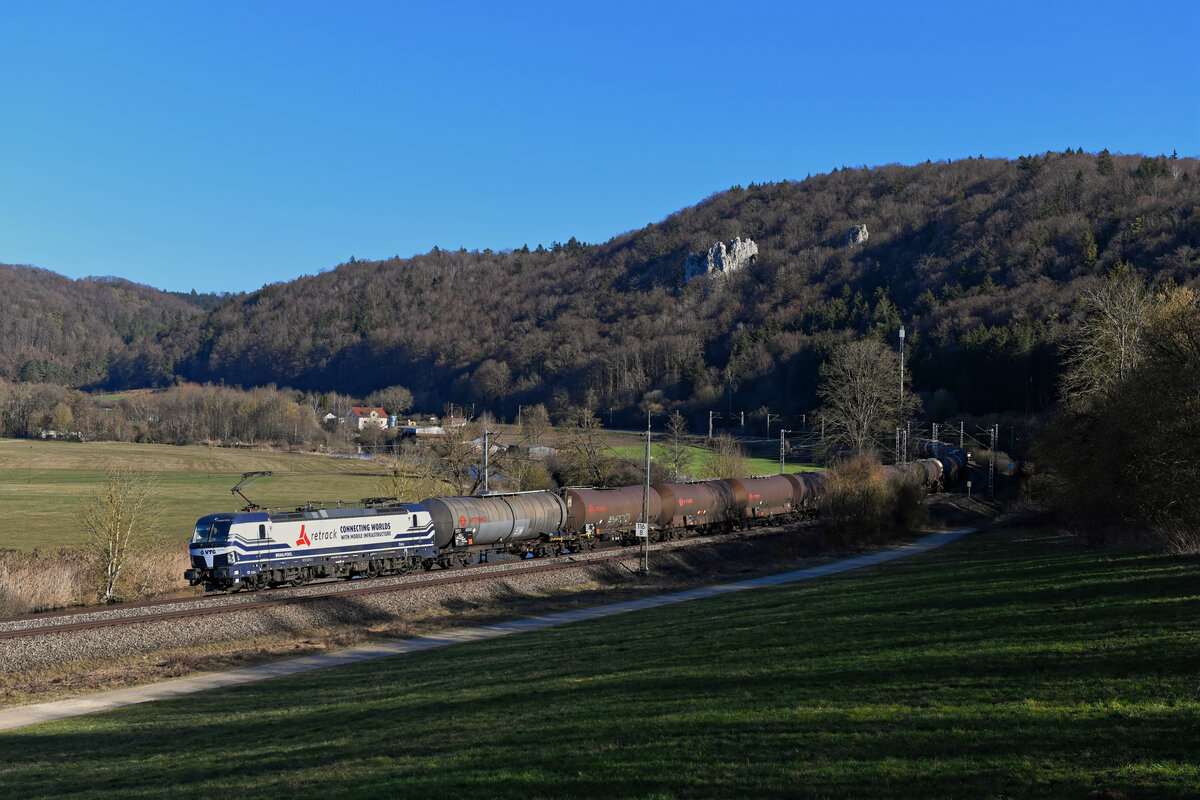 Ende Februar steht die Sonne noch nicht hoch und die Schatten werden am Nachmittag schnell wieder lang. Gerade noch rechtzeitig passierte am 28. Februar 2021 die 193 825 mit einem Kesselwagenzug aus Ungarn die Fotostelle bei Dollnstein. Kurz nach dem Aufnahmezeitpunkt lag der Gleisbereich bereits im Dunkeln. Die von Retrack erbrachte Zugleistung wurde an diesem Tage aufgrund von Baurabeiten zwischen Regensburg und Nürnberg über das Altmühltal umgeleitet.   