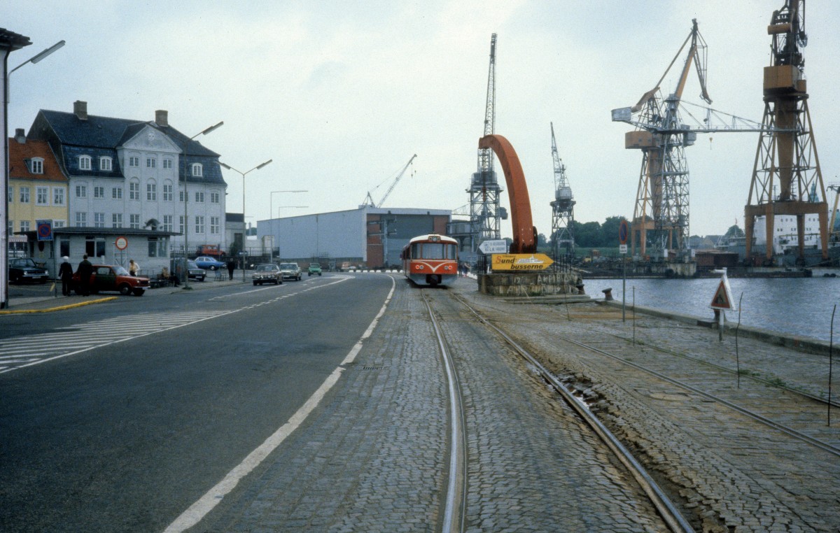 HHGB (Helsingør-Hornbæk-Gilleleje-Banen) am 5. Juni 1981: Triezug (Ys + Ym) in Richtung Gilleleje in der Havnegade (: Hafenstrasse) in Helsingør. - Im Hintergrund sieht man einen Teil der 1882 geöffneten und 1983 stillgelegten Schiffswerft, Helsingør Skibsværft.