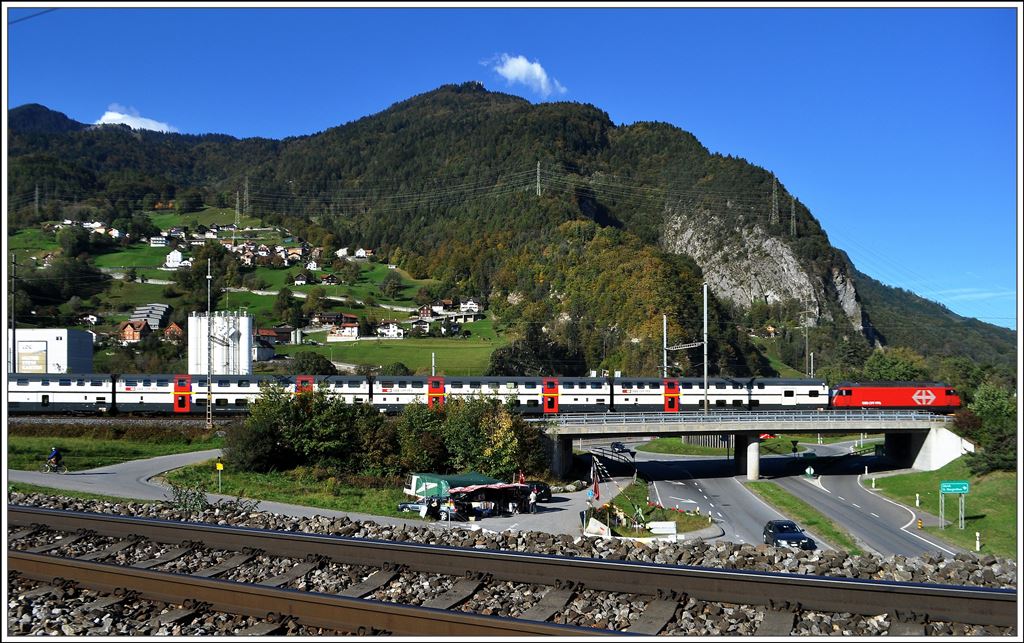 IC 570 von Chur nach Zürich HB verlässt Landquart. Im Vordergrund das RhB-Trassee Richtung Malans, dahinter der Verkaufsstand vom Sockenhitsch, hinter dem Zug Mastrils mit dem Pizalun. Auf dessen Felsspitze führt eine Eisenleiter und ermöglicht einen 360 Grad Blick. (09.10.2014)