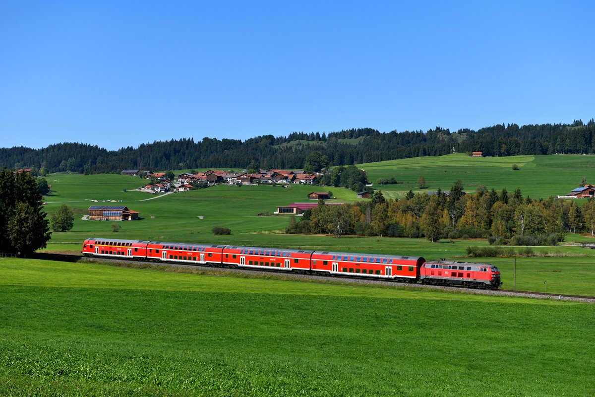 In der Gegend von Hopferau ergeben sich einige Fotomotive, so auch dieser Blick auf den kleinen Weiler Heimen. Am 20. September 2018 schob 218 497 den RE 57511 von Füssen nach München HBF und wird bald den ersten Haltepunkt Weizern-Hopferau erreichen. 