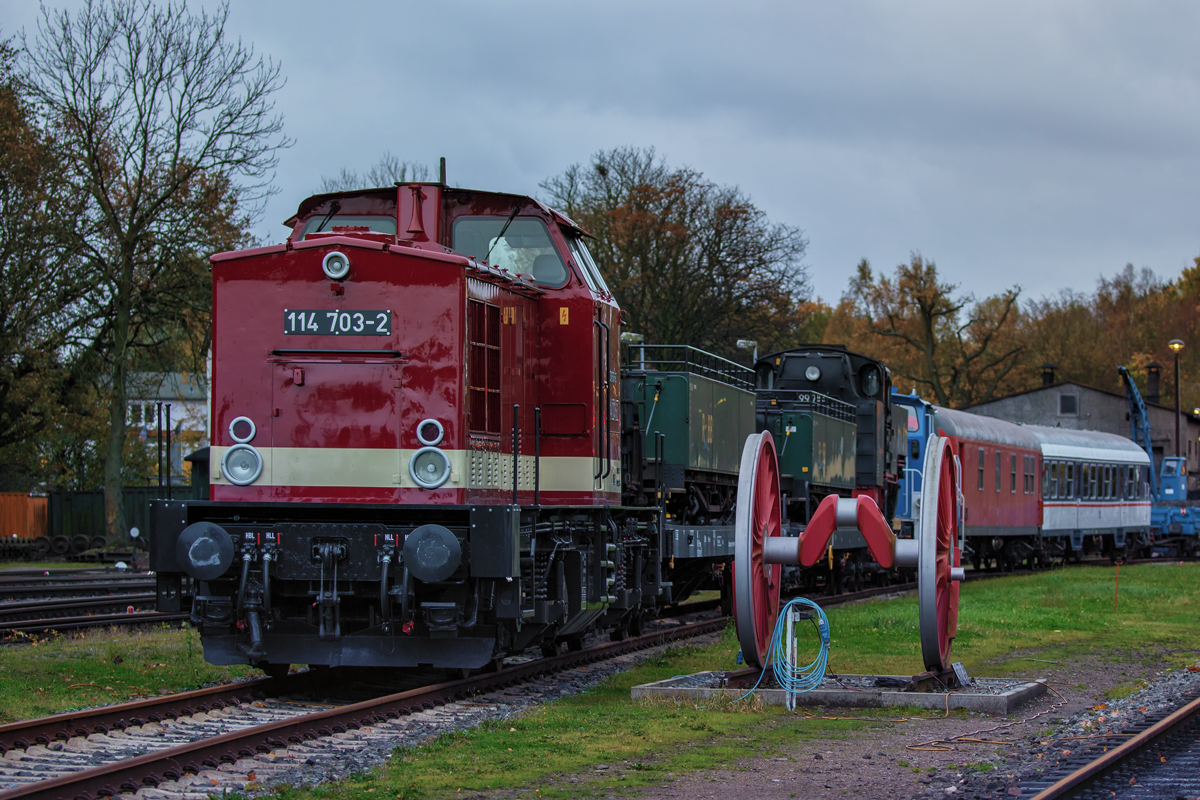  In Putbus stehende Lok 114 703 mit beladenen Schmalspurtransportwagen, auf denen Schmalspurwagen und die Lok 99 783 stehen. - 02.11.2017 - Vom Reisendenübergang aufgenommen. 

