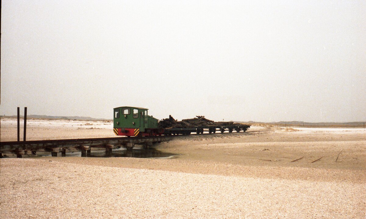 Inselbahn Spiekeroog__Schöma-Lok 4 von 1957 mit Güterwagen transportiert ausgediente Holzschwellen zum Strand.__April 1984