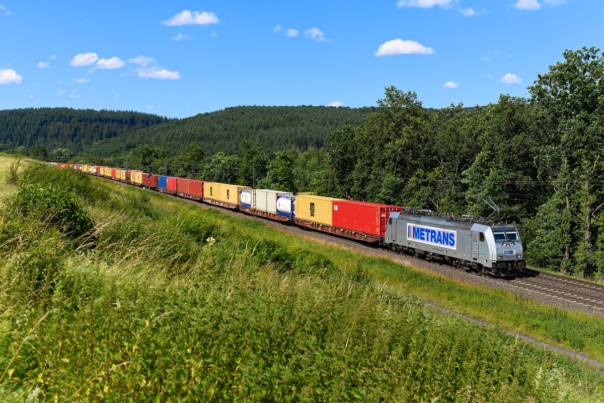 Komplett beladen, aber etwas verspätet durchfuhr am 28. Juni 2024 der Metrans-Containerzug DGS 88911 von Bremerhaven Kaiserhafen nach München Riem Ubf das osthessische Haunetal. Zuglok war an diesem Tage die 386 023. 