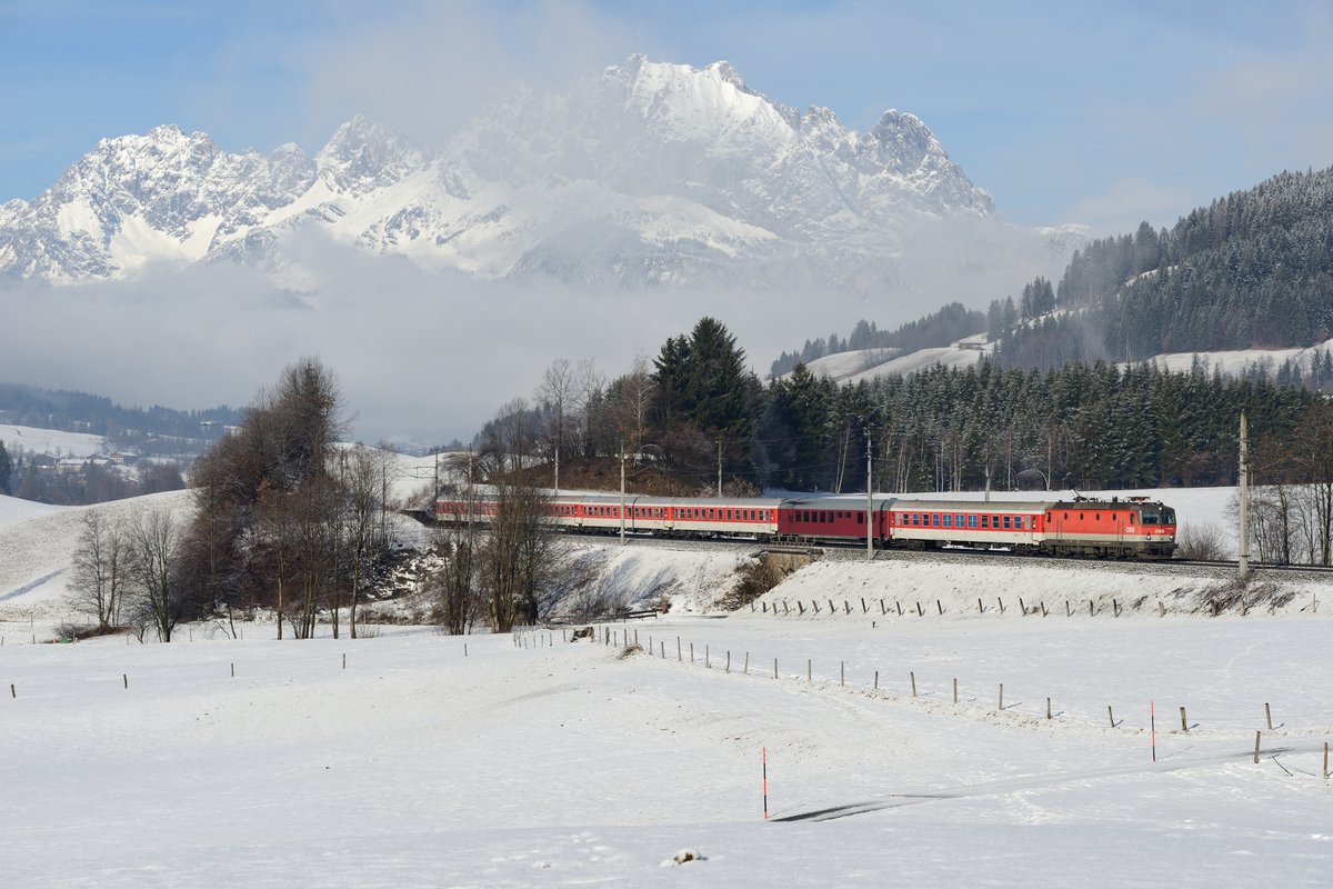 Letzter Turnuszug in Richtung Saalfelden war am 08. Februar 2014 der D 13417. Zuglok war die 1144.205. Der Wilde Kaiser thront über der Szenerie und glücklicherweise lag in der Gegend um Fieberbunn im schneearmen Winter 2013/2014 zumindest eine geschlossene Schneedecke.