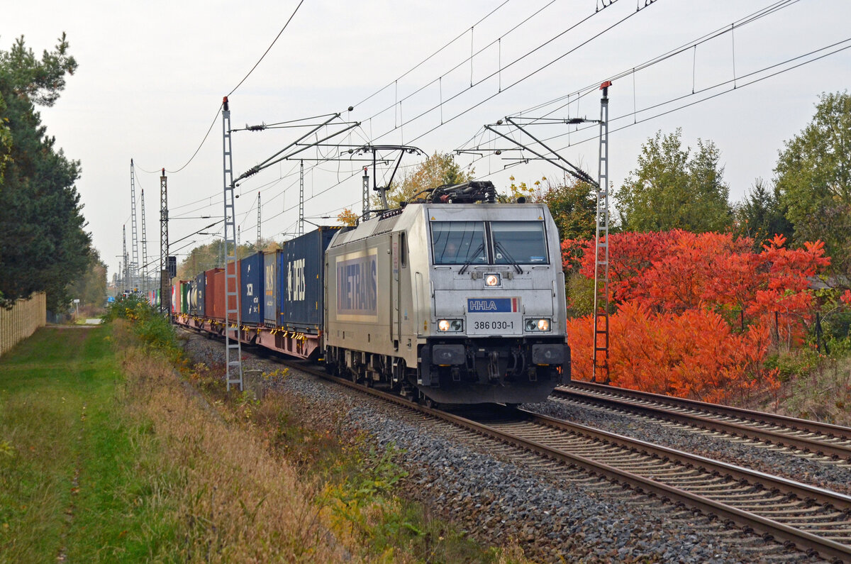 Mit einem Containerzug am Haken rollt 386 030 der Metrans am 27.10.24 am herbstlich gefärbten Farn vorbei. Hier passiert der Zug Wittenberg-Labetz in Fahrtrichtung Falkenberg(E). 