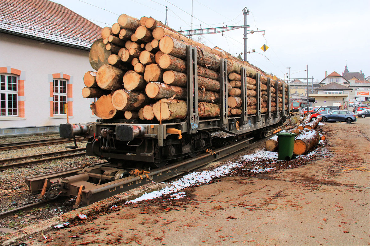 Mit Holz beladener Normalspurwagen auf zwei Rollschemeln der Jurabahn CJ in Tramelan. Solche Zusammenstellungen konnten früher auf Meterspurbahnen verschiedentlich beobachtet werden; heute dürfte das Bild Seltenheitswert haben. Hinten wartet der GTW 633 auf die Abfahrt zur Talstation in Tavannes. 19.Februar 2018.  