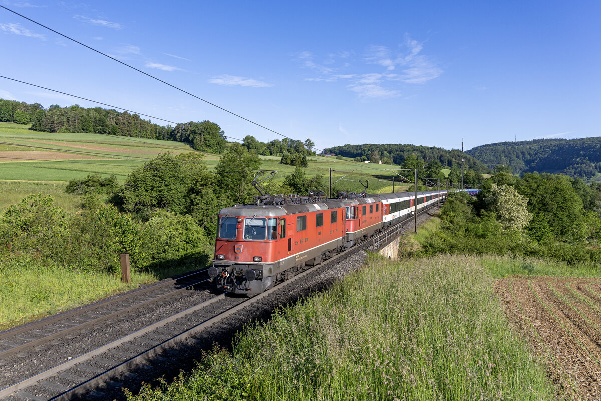 Re 4/4 II 11195 und 11299 sind mit dem NJ 403 aus Amsterdam in Richtung Zürich HB unterwegs, aufgenommen bei Hornussen AG am Morgen des 26.05.2024.