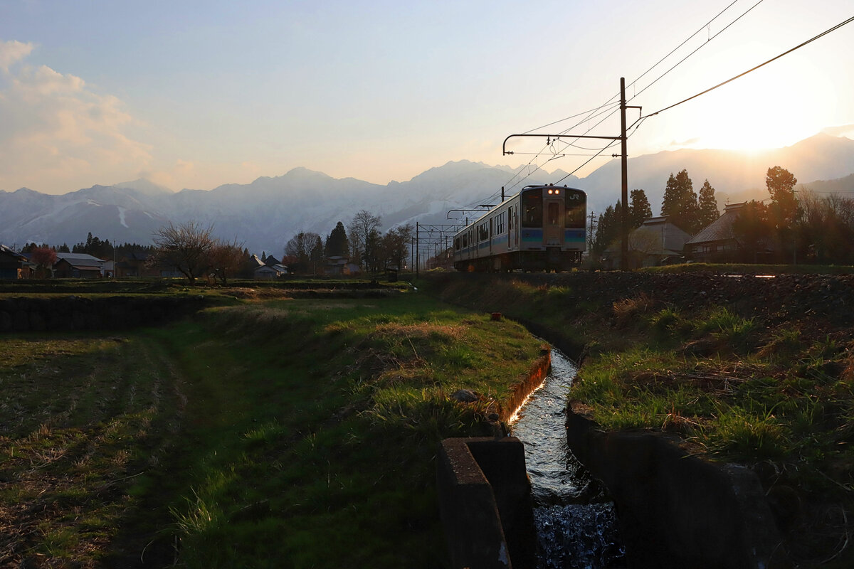 Sonnenuntergang in Shinano Moriue in den japanischen Alpen. Durchfahrt des Zweiwagenzugs E127-108. 20.April 2022 