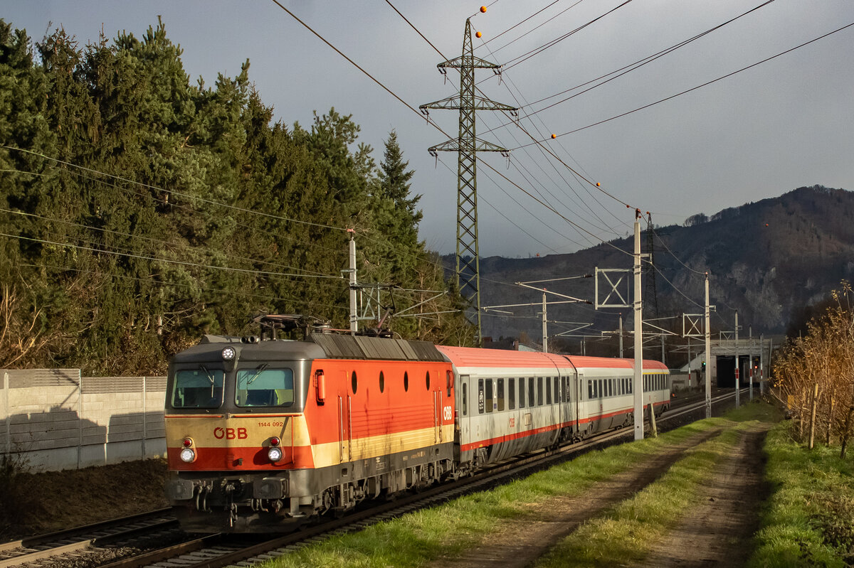 Stübing. Die 1144 092 ist die letzte Maschine der ÖBB, welche aktuell noch im traditionellen Schachbrett-Design lackiert ist. Am 29.11.2024 zieht die Lokomtovie den Intercity 501 von Linz nach Graz, hier in Stübing.