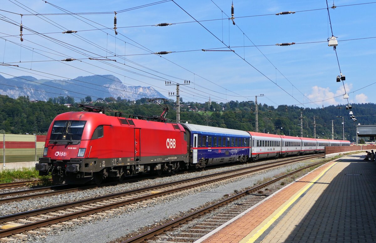 Trotz angespannter Wagensituation sind die ÖBB bemüht, an starken Reisetagen Entlastungszüge zu führen. Ein solcher Zusatzzug ist der D 19780, der von Wien Hbf nach Feldkirch verkehrt. Vergangenen Sommer kamen hier auch die als  Südbahn-Express  beschrifteten Wagen der Baureihe 20-94 zum Einsatz, die eigentlich auf der Semmering-Route unterwegs sein sollten. Hier durchfährt der von 1016 001 geführte Verstärkerzug am 31.08.2024 den Bahnhof Kundl in Richtung Innsbruck.