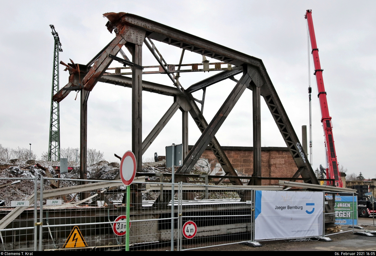 VDE 8 Komplexmaßnahme Halle Rosengarten–Angersdorf
▶ Standort: Halle Rosengarten

Die Reste der 1941 erbauten Argentinierbrücke am vergangenen Samstagnachmittag. In der Nacht von Freitag auf Samstag wurde der 70 Tonnen schwere Stahlriese vom größten mobilen Kran der Welt ausgehoben. Eigentlich sollte dies bereits um 23:00 Uhr geschehen, doch wegen der Eigenwilligkeit solcher Bauwerke war es erst um 7:00 Uhr soweit. Seitdem lief die eigentliche Demontage auf Hochtouren, sodass bei meiner Ankunft nur noch etwa ein Drittel der Brücke vorhanden war. Das Bild entstand hinter einer Absperrung auf der Kasseler Straße.
Wer die Brücke mal schweben sehen will, dem kann ich eindrückliche Bilder aus der Nacht am Ende dieser Seite empfehlen:
https://www.vde8.de/halle-rosengarten-08.02.2021

🕓 6.2.2021 | 16:05 Uhr