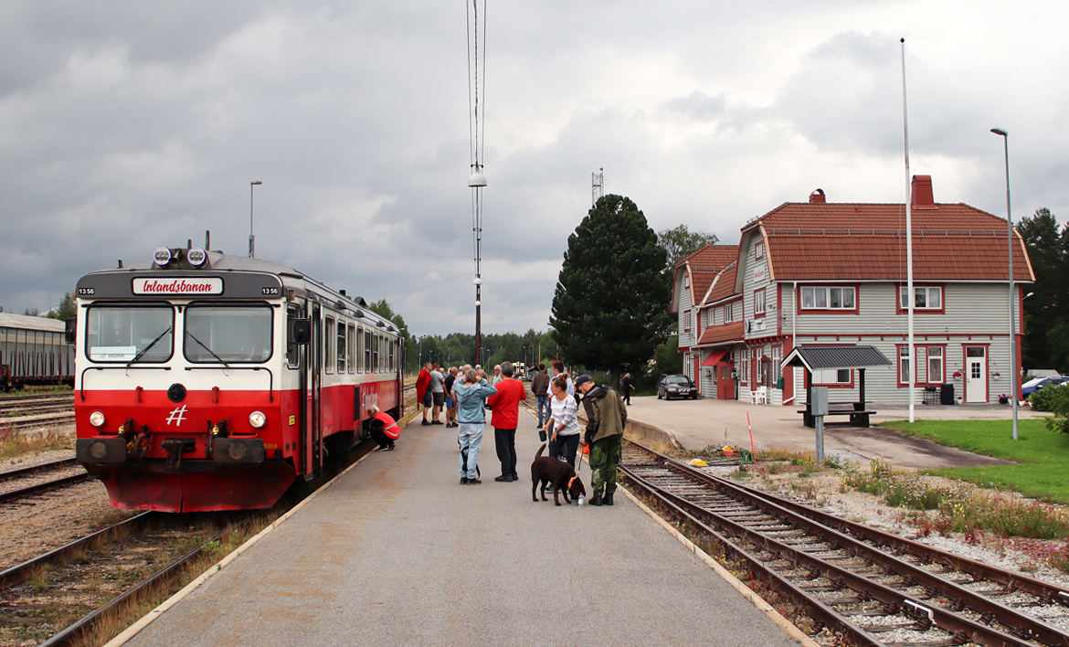 Verkehrt einmal täglich im Sommer: die Inlandsbanan von Oestersund nach Sveg, an diesem Tag Dieseltriebwagen 1356. Ein paar Minuten Aufenthalt, die Lokführerin kontrolliert den Triebwagen und die Fahrgäste geniessen die frische Luft. Rechts das schmucke Bahnhofgebäude. Sveg, 8.8.2024