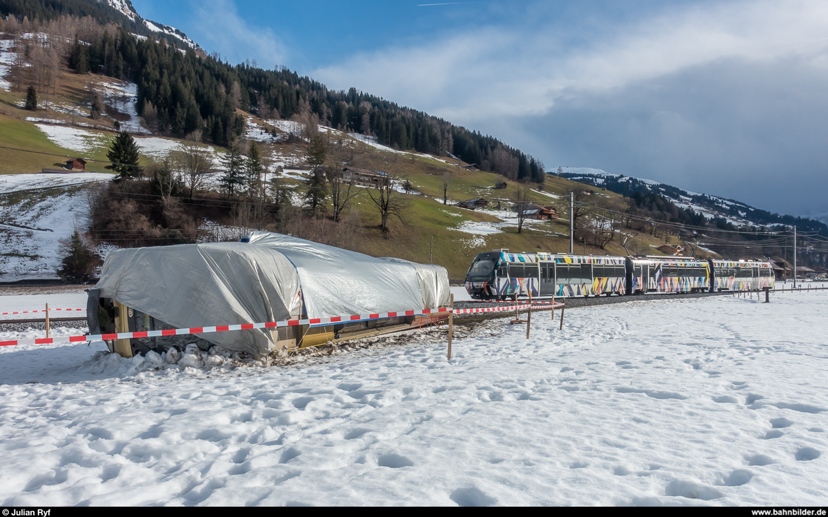 Vom Winde verweht. Der Steuerwagen vom Triebwagen 5004 liegt am 8. Januar 2018 zwischen Boden und Matten neben dem Gleis. Der Wagen wurde am 3. Januar 2018 von Sturm Burglind in voller Fahrt vom Gleis geweht (siehe auch: <a href= https://www.bernerzeitung.ch/region/oberland/lenk-mehrere-verletzte-bei-entgleisung-eines-bahnwagens/story/31071047 >https://www.bernerzeitung.ch/region/oberland/lenk-mehrere-verletzte-bei-entgleisung-eines-bahnwagens/story/31071047</a>).<br>
Dahinter fährt Be 4/4 5001 als Regio Lenk - Zweisimmen vorüber.