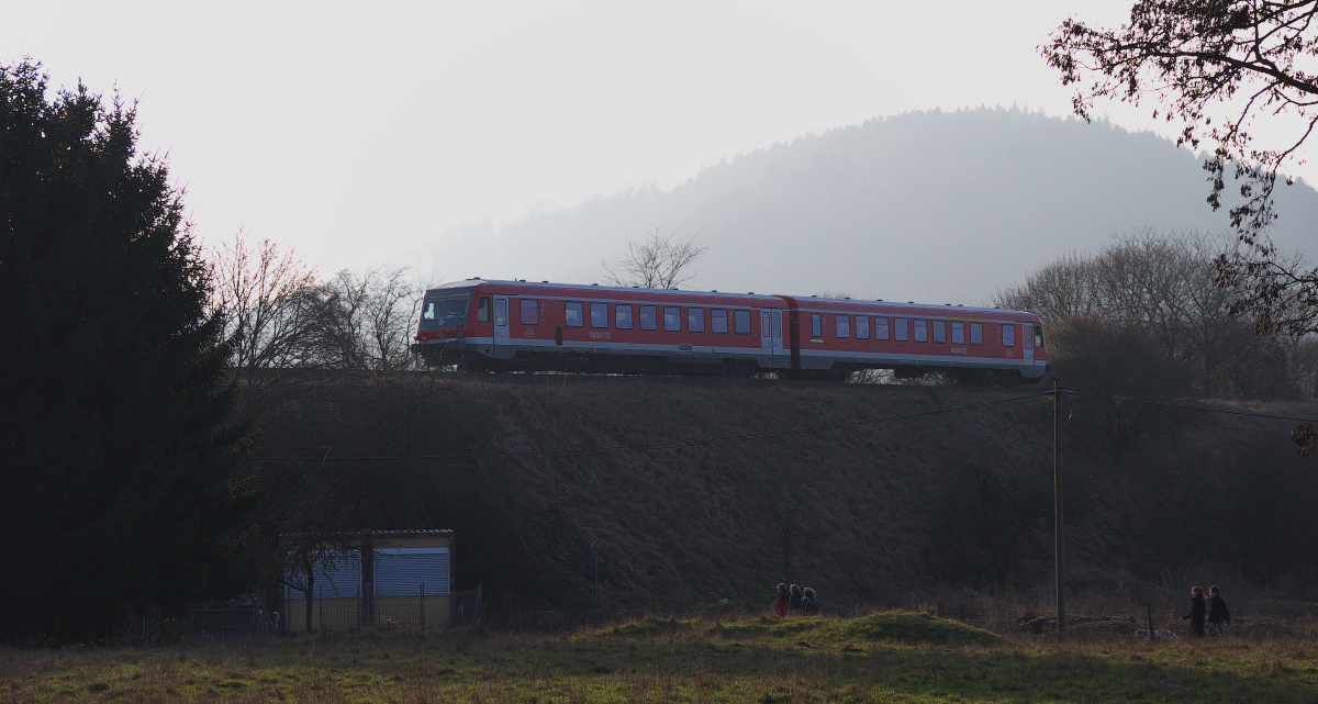 Wenn sich die Sonne hinter den Bergen verabschiedet,dann zieht Dunst auf und Kälte schleicht über die Landschaft.
Der  Niedtalexpress  fährt in diese Abendstimmung hinein.
Der Triebwagen der Baureihe 628 hat in Form einer Brücke die KBS 685 überquert und fährt nun auf einem hohen Damm der Saar entgegen.
Zuvor wird noch eine Landstraße überquert und dann erreicht der Damm die Saarbrücke bei Rehlingen.
Bahnstrecke 3212 (F Bouzonville) - Niedaltdorf Grenze - Dillingen Saar am 22.01.2014