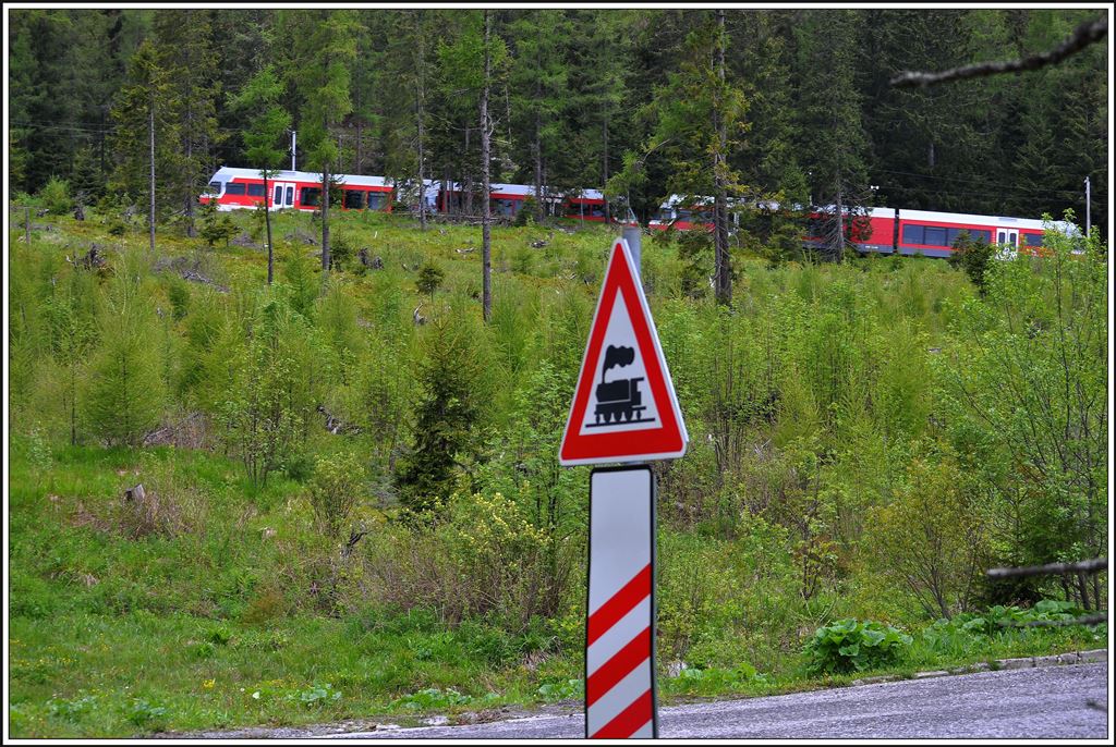 Zwei Stadler GTW kommen von Štrbské Pleso herunter und überqueren bei der Haltstelle Popradské Pleso diese Nebenstrasse. (03.06.2014)