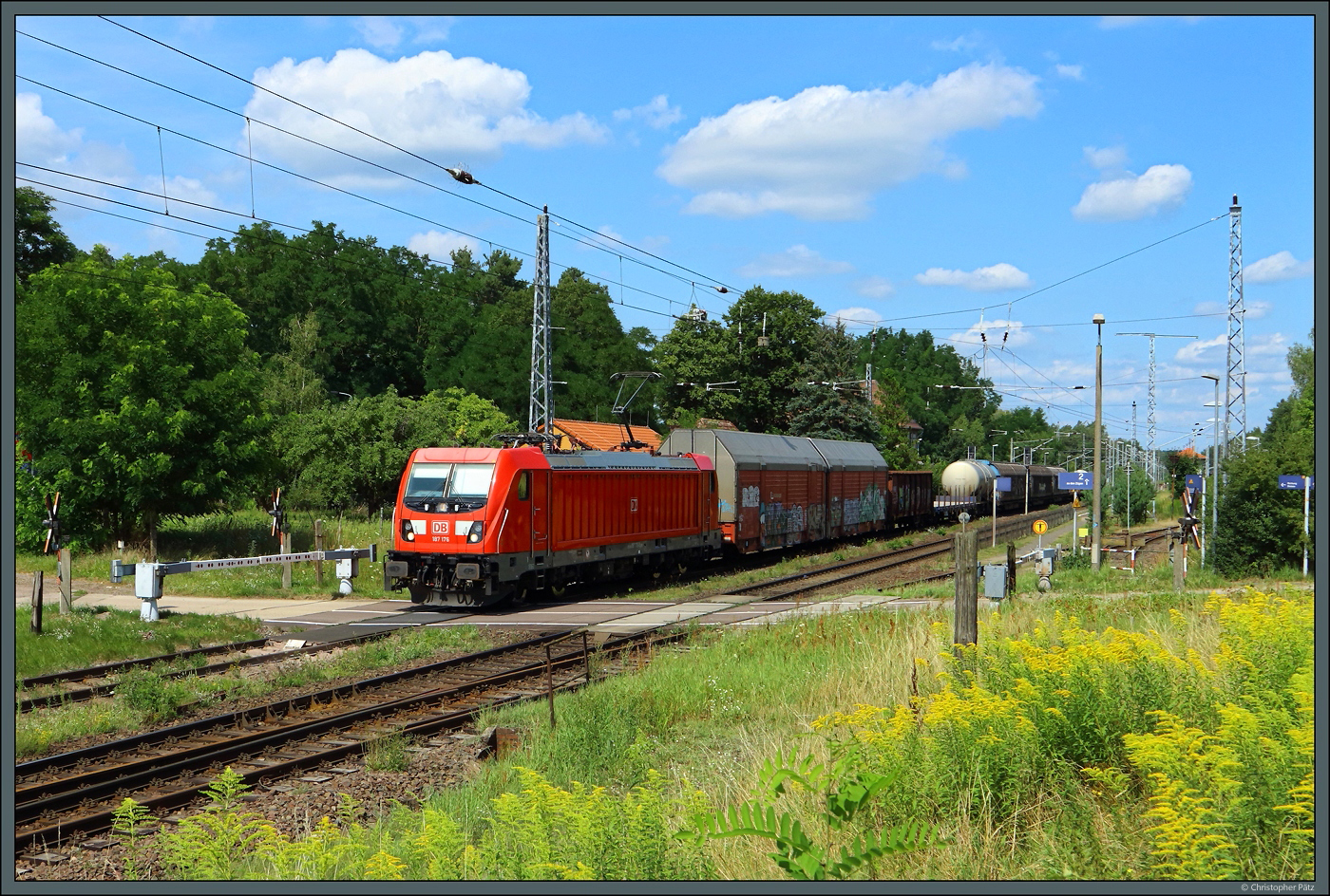 187 176 der DB Cargo passiert am 03.08.2024 mit einem gemischten Güterzug den BÜ im Bahnhof Medewitz.