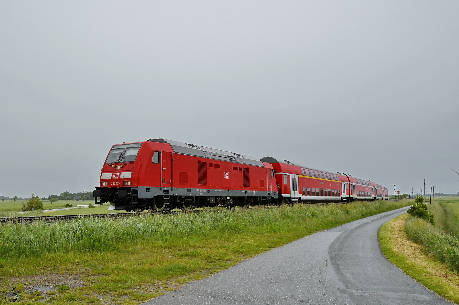 Der von der Diesellokomotive 245 005 gezogene RE6 macht sich nach einem kurzen Stop weiter auf den Weg nach Westerland. (bei Nibüll, Juni 2024)