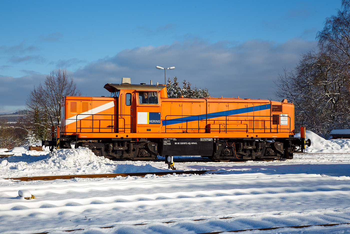 Die an die Hering Bau GmbH & Co. KG (Burbach) vermietete 291 972-8 (98 80 3291 972-8 D-NRAIL) eine Sonderbauart MaK G 1600 BB der Northrail (Hamburg) ist am 09 Januar 2021 auf dem Betriebshof der Westerwaldbahn auf der Bindweide bei Steinebach/Sieg.

Die MaK G1600 BB der Sonderbauart wurde 1971 von MaK Maschinenbau GmbH im Werk MaK-Kiel-Friedrichsort unter der Fabriknummer 1000516 für die Bayerische Braunkohlen-Industrie AG (BBI AG) in Schwandorf gebaut und als M 19 geliefert.
Die BBI AG hatte eine eigene Werksbahn womit die Braunkohle vom Abbau bei Wackersdorf ins sieben Kilometer entfernte Kohlekraftwerk Schwandorf transportiert wurde. Im Jahr 1981 wurden hier täglich zwischen 20.000 und 25.000 Tonnen Kohle verfeuert.
Weiterer Lebenslauf der 291 972-8:
1982 ging die BBI AG in die Bayernwerk AG (BAG) über
1986  Ausbau der Hagenuk Dampfheizkesselanlage
2000 Bayernwerk wurde nun e.on Kraftwerke GmbH
2002 wurde die Lok an die OHE - Osthannoversche Eisenbahnen AG, in Celle verkauft und fuhr nun als OHE 120076. 
2007 erhielt die NVR-Nummer 98 80 3291 972-8 D-OHE
2011 ging die Lok an die northrail GmbH in Hamburg, wo sie seitdem als Mietlok unter der UIC-Nummer 98 80 3291 972-8 D-NTS fährt

Technik:
Die MaK G 1600 BB ist eine dieselhydraulische Lokomotive, von denen 16 Stück (mit 1.600 PS), sowie 3 Stück in Sonderbauart (mit 1.000 PS), zwischen 1971 und 1979 von der Firma MaK Maschinenbau GmbH, Werk MaK-Kiel-Friedrichsort, gebaut wurden. Zu der Sonderbauart gehört auch diese Lok hier.

Analog zur G 1300 BB wurde auch aus der an die DB gelieferten V 90 eine Privatbahnversion entwickelt, die in fünf Exemplaren als V 90 P gebaut wurde und im Wesentlich der DB-Variante entsprach, jedoch einen hauseigenen Motor erhielt. Nachdem sich jedoch weniger die Privatbahnen als vielmehr die DB selbst für diese Loks interessierten, entstand bei MaK eine weitere Variante der V 90, die spezieller auf die Bedürfnisse der Privatbahnen abzielte und z.B. eine 24V-Elektrik erhielt. Diese unterscheidet sich auch deutlich in ihren Hauptabmessungen von den DB-Maschinen. Ein wenig sieht man der Lok die Verwandschaft mit der V 90 an.

Der eingebaute Achtzylinder-Motor des Typs MaK 8M282AK leistet 1.180 kW (1.600 PS) bei 1.000 U/min, die Lok erreicht je nach Getriebeeinstellung eine Höchstgeschwindigkeit von 44 bis 80 km/h. Das Dienstgewicht liegt je nach Ausrüstung zwischen 80 und 104 Tonnen. Bei den Lokomotiven mit einer Höchstgeschwindigkeit von 44 km/h entfällt der Streckengang.

Sonderbauart der MaK  G 1600 BB (wie diese Lok):
Für den Einsatz vor Kohlezügen in Tagebauen benötigte die Bayerische Braunkohlen-Industrie (BBI) Loks mit eingebauter Dampfheizung. Eine Leistung von 1.100 PS wurde dabei als ausreichend erachtet.
So wurden 1971 und 1972 von MaK für die BBI 3 Lokomotiven in Sonderbauart gebaut. Um ausreichend Platz für den Hagenuk Dampfheizkesselanlage  zu haben, wurden Fahrwerk und Aufbauten von der G 1600 BB übernommen. Die Antriebstechnik wurde der G 1100 BB, einem Sechszylinder-MaK-Dieselmotor mit Turbolader und Ladeluftkühlung vom Typ 6M282 AK mit 1.100 PS) übernommen. Der zusätzlich gewonnene Platz, durch Verlagerung des Druckluftgerüstes unter das Führerhaus, konnte für den Einbau des Heizkessels genutzt werden, welcher mittlerweile entfernt worden ist. Äußerlich waren die Loks an dem zweiten Auspuff (für die Dampfheizkesselanlage) auf der Führerhausrückseite und dem kleineren Kühler, der der geringeren Leistung angepasst wurde erkennbar.  Die Loks wurden vom Hersteller verwirrenderweise ebenfalls als G 1600 BB bezeichnet. Da der Dampfheizung ausgebaut wurde, entfiel auch der zweite Auspuff.

.TECHNISCHE DATEN der G1600 BB in Sonderbauart:
Gebaute Stückzahl: 3  (und 16 Standardloks)
Spurweite: 1.435 mm (Normalspur)
Achsformel: B'B'
Länge über Puffer: 14.320 mm
Drehzapfenabstand: 7.000 mm
Achsstand im Drehgestell: 2.500 mm
Treibraddurchmesser:  1.100 mm (neu)
Höhe: 4.200 mm
Dienstgewicht: 80 t
Radsatzfahrmasse: 20 t 
Kleinster bef. Halbmesser:  60 m
Höchstgeschwindigkeit: 48 km/h (Rangiergang) / 74 km/h (Schnellgang)
Dieselmotor:  MaK 6-Zylinder Reihenmotor mit Abgasturbolader und Ladeluftkühlung vom Typ vom Typ 6M282 AK
Installierte Leistung: 809 kW (1.100 PS)
Nenndrehzahl: 1.000 U/min
Anfahrzugkraft: 265kN 
Tankvolumen: 3.500 l
Funkfernsteuerung: Theimeg EC/LO
Bremse: KE-GP2mZ

Quellen: Northrail, loks-aus-kiel.de, wikipedia.org
