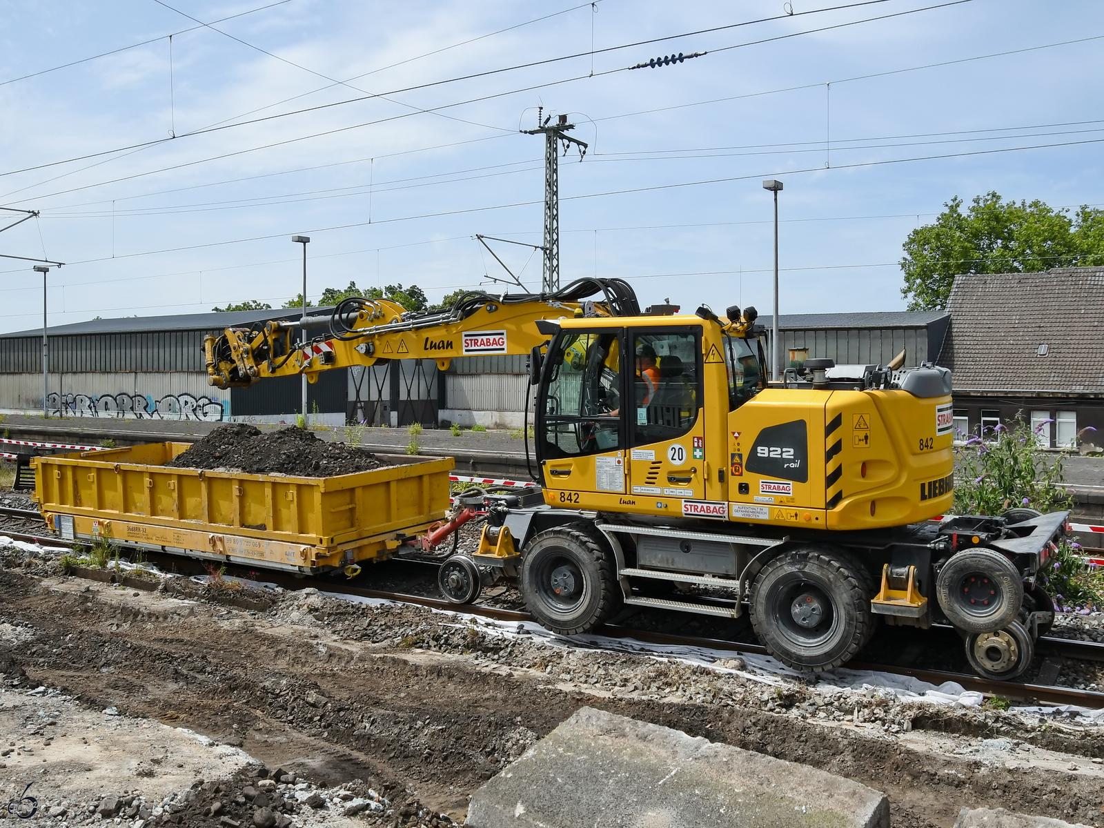 Ein Zweiwegebagger LIEBHERR 922 Rail ist hier mit einem Schwerlastkleinwagen auf Schienen zu sehen. (Wanne-Eickel, Juni 2024)