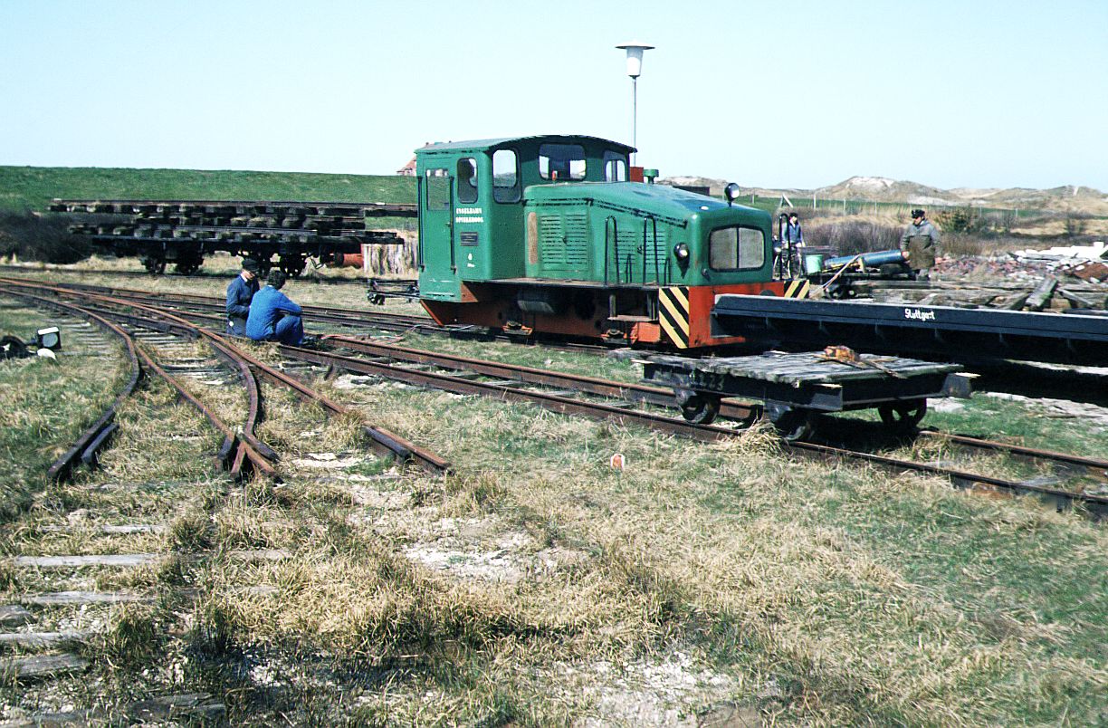 Inselbahn Spiekeroog__April 1984. Pause muß mal sein. SCHÖMA-Lok 4 von 1957 mit Flachwagen. Der ungefähre Bestimmungsbhf. dieser Fahrzeuge steht schon  angeschrieben :  Stuttgart , wobei das Straßenbahnmuseum Stuttgart (SMS) seit März 1984 seinen Sitz in Schönau/Odenwald hatte.